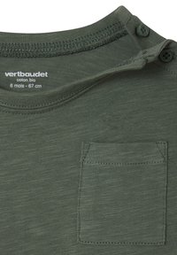 Olivgrünes Baumwoll-T-Shirt mit Rundhalsausschnitt, zwei Knöpfen an der Schulter und einer kleinen Brusttasche. Weicher, strukturierten Stoff.