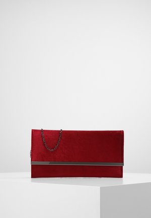 Pochette rouge rectangulaire avec un détail de barre métallisée argentée et une fine chaîne argentée, posée sur une surface blanche.