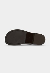Semelle d'une chaussure habillée en cuir noir avec bord cousu et taille 37 imprimée près de la voûte plantaire, présentée sur fond blanc.