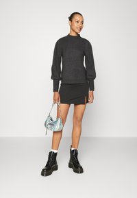 Dark grey ribbed sweater with high neck, black mini skirt with side slit, black lace-up boots, and iridescent handbag with silver chain.