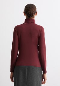 Mörkröd långärmad topp med hög krage, gjord av ett slätt tyg, har en figursydd design, spänd i midjan, med en enkel baksida.
