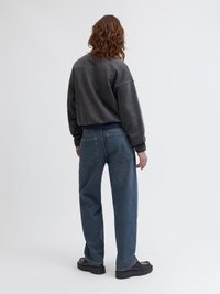 Υπερμεγέθη γκρι φούτερ, χαλαρές μπλε τζιν παντελόνες και χοντρές μαύρες γαλότσες. Το σύνολο διαθέτει casual, άνετο στυλ με υφασμάτινη υφή.