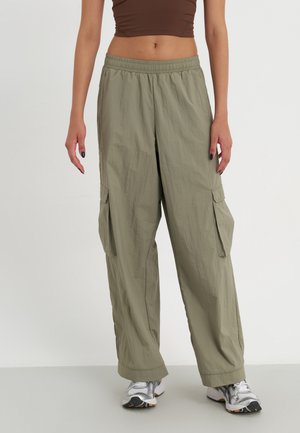 Lightweight, olive-green cargo pants with an elastic waistband, side pockets, and a loose fit, paired with gray and white sneakers.