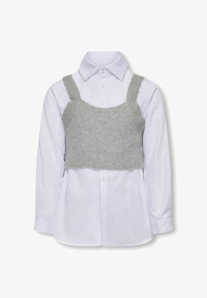 Gray knitted crop top over a white long-sleeve button-up shirt. Features straps and ribbed texture on the top. Button detail on the shirt.