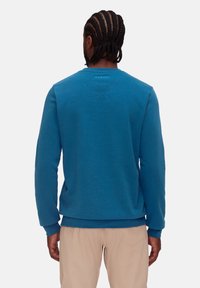 Blå sweatshirt tillverkad av mjukt material, med rund halsringning, långa ärmar och en texturerad baksida med logodetalj vid halsringningen.