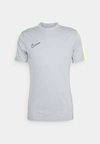Camiseta atlética gris de manga corta, con detalles en amarillo neón en los hombros y un logo negro de Nike en el pecho.