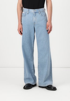 Lichtblauwe wijde jeans van denim. Heeft vijf zakken en een ritsluiting. Strak om de taille, losvallend door de benen.