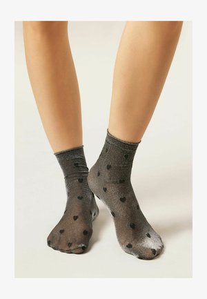 Calzini neri trasparenti con texture scintillante, caratterizzati da cuori neri sparsi. Materiale morbido, lunghezza a metà polpaccio e polsino elastico ripiegato.