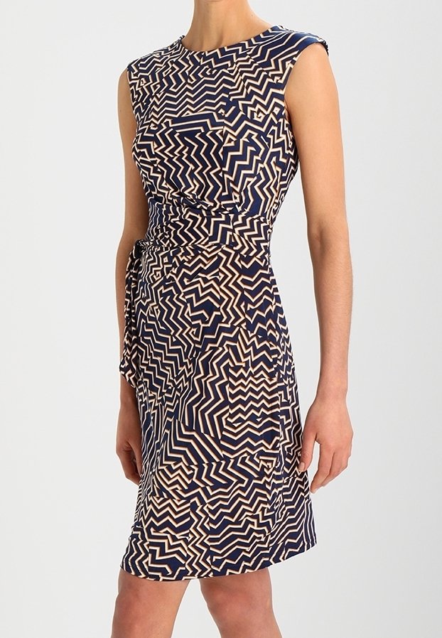 Robe sans manches longueur genou avec motif géométrique en zigzag bleu marine et beige et ceinture nouée à la taille.