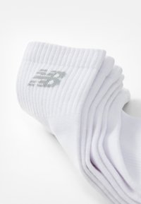 Bijele pamučne čarape s rebrastom teksturom i sivim New Balance logom. Dizajn je jednostavan s preklopom za udobnost.