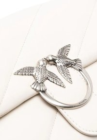 Sac à main en cuir blanc avec un fermoir en métal argenté en forme de deux oiseaux se faisant face, orné d'ailes texturées.