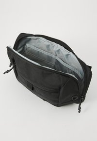 Black zippered pouch with gray interior lining, multiple internal pockets, and a textured mesh compartment, placed on a white surface.