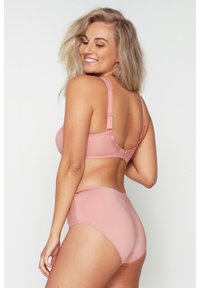 Ensemble de lingerie rose comprenant un soutien-gorge avec des bretelles réglables et une culotte taille haute assortie, en tissu lisse et avec un minimum de détails.