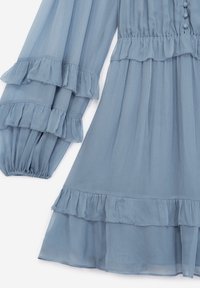 Abito in chiffon azzurro chiaro con maniche lunghe a volant, caratterizzato da strati sovrapposti, dettagli con bottoni sul davanti e una silhouette fluida.