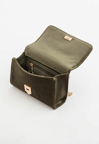 Oliven grøn velour taske med en gold firkantet lås, udstyret med en åben flap og en indvendig lomme med lynlås til opbevaring.