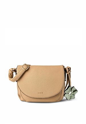 Bolso bandolera de cuero color canela con correa ajustable, cierre de solapa y un charm gris con forma de flor adjunto al costado.