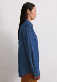 Denim overhemd in donkerblauw met lange mouwen, twee voorzakken, knoopsluiting en een comfortabele pasvorm. Textuurstof, eenvoudig kraagontwerp.