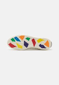 Gumowa podeszwa sneakersów z teksturowaną kremową powierzchnią oraz kolorowymi geometrycznymi wzorami w czerwonym, żółtym, zielonym, niebieskim, pomarańczowym i fioletowym.