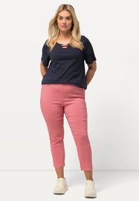 Tmavě modrý top s krátkým rukávem a červenými knoflíky, doplněný o červenobílé kárované krátké kalhoty a bílé tenisky.