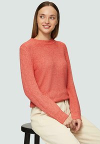 Korali akrylowy sweter z okrągłym dekoltem i długimi rękawami, z teksturowanym wzorem i ściągaczami na rękawach, zestawiony z jasnymi spodniami.