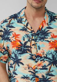 Kurzärmliges, hawaiianisches Hemd mit einem bunten Blumen- und Palmenprint auf einem hellblauen Hintergrund; mit Knopfleiste.