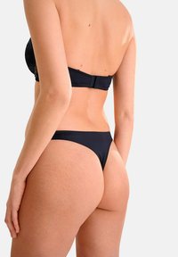 Ensemble bikini noir avec un haut sans bretelles et un bas tanga taille basse, en tissu lisse, avec un minimum de détails et un design classique.