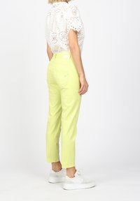 Ljust gula byxor i bomull med rak passform, som har bakfickor och som är i kombination med vita sneakers.