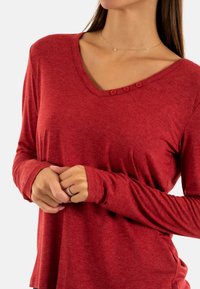 Rode lange mouwen shirt met een V-hals, drie-knopen detail op de halslijn en zachte, gestructureerde stof met een relaxte pasvorm.