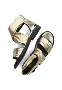 Gouden metallic sandalen hebben een open teenontwerp, gekruiste banden en een zwarte rubberen zool. De ritssluiting aan de achterkant zorgt voor gemakkelijk aan- en uittrekken.
