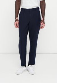 Pantaloni cu croială marină, cu o textură netedă, față dreaptă și picioare conice. Asortați cu adidași albi pentru un contrast de culoare și stil.