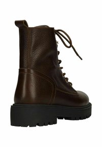 Bruine leren enkellaars met een gestructureerde afwerking, ronde neus en dikke zwarte rubberen zool. Voorzien van een vetersluiting aan de voorkant en een trek-tab aan de achterkant.