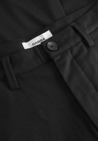 Svarta byxor av slät tyg med knäppning, veck framtill och en varumärkesetikett sydd i midjebandet.