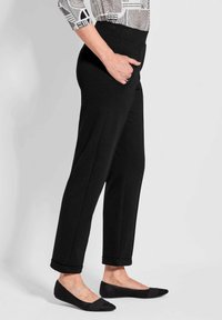 Zwarte op maat gemaakte broeken met een soepele textuur, voorzien van een hoge tailleband en opgerolde manchetten, gecombineerd met zwarte gaasballerina's.