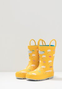 Żółte gumowe kalosze z wzorem chmur i parasolek w kolorach różowym, fioletowym i niebieskim. Zawierają uchwyt do łatwego zakładania.