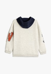 Felpa grigia con cappuccio blu navy. Presenta una grande 'W' arancione sulla manica e testo bianco sul lato opposto. Tessuto morbido e texturizzato.