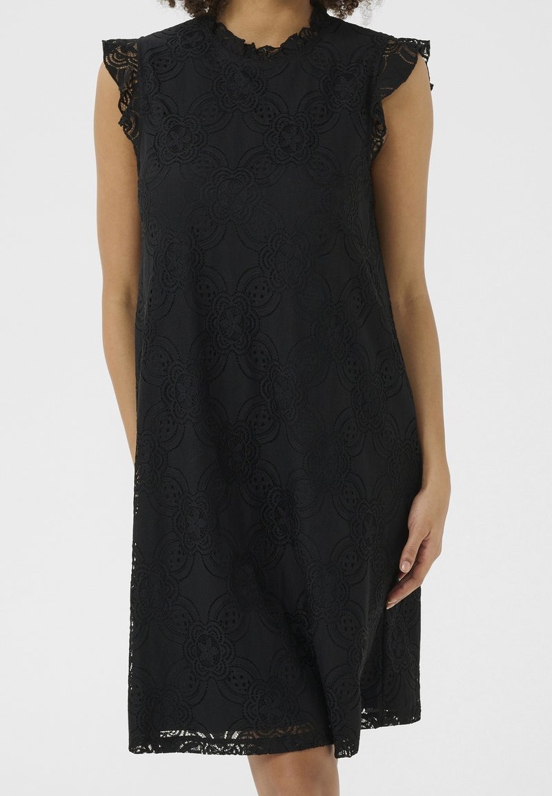 Černé krajkové šaty s květinovým vzorem, krátkými volánkovými rukávy a kulatým výstřihem. Texturovaná látka má složité výřezy.
