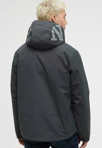 Szary, kapturowy kurtka o matowym wykończeniu. Posiada wyraźne logo z tyłu, elastyczne mankiety oraz luźny krój.