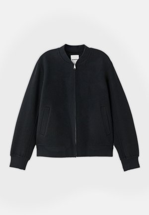 Must must jacket, mis tekstureeritud kangast, millel on tõmblukk ees, soonilised mansetid ja kaks külgtaskut. Lihtne, minimalistlik disain.
