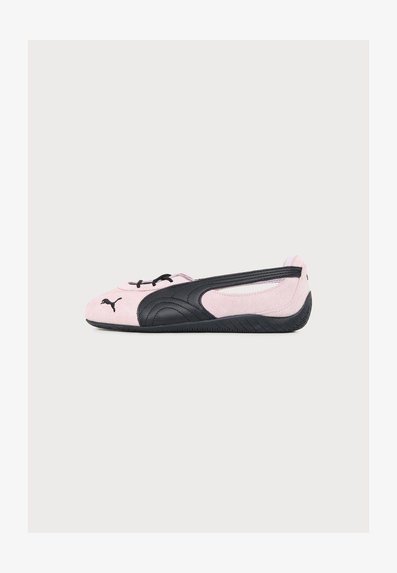 Baskets plates ballerines Puma rose et noire avec lacets à l'avant et semelle noire, vues de côté sur un fond uni.