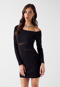 Schwarzes Minikleid mit langen Ärmeln und asymmetrischem Ausschnitt, mit transparenten Mesh-Einsätzen an der Taille und klassischem, figurbetontem Design.