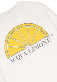 Krämfärgad tyg med en stor gul citronklyfta grafiskt tryck på baksidan, med texten "ACQUA LIMONE" i svart nedanför.