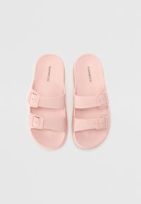 Rosa halkande sandaler med två justerbara remmar och spännelement. Tillverkade av ett slätt material med en lätt glans. Platt sula design.