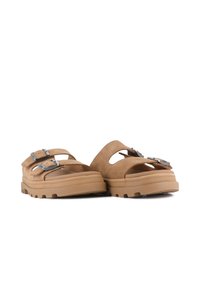 Hnědé semišové sandály s dvěma nastavitelnými přezkami, otevřenou špičkou a texturovanou gumovou podrážkou pro lepší grip. Ozdobené špičatými výřezy.