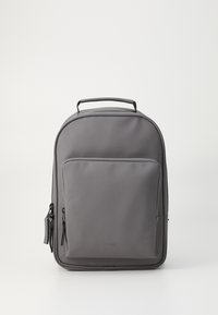Mochila impermeable gris con un diseño elegante, asa superior y un bolsillo frontal con cremallera. Presenta una textura suave y un branding sutil.