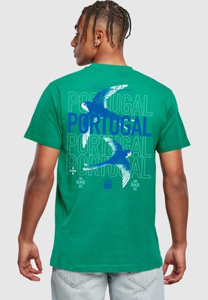 Žalias medvilninis marškinėliai su mėlyno paukščio grafika ir tekstu "PORTUGAL". Lygus audinys, trumpomis rankovėmis ir klasikinio pjaustymo.