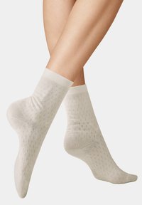 Light beige knee-high socks with a textured diamond pattern, smooth fabric, and elastic cuffs. Appropriate for casual wear.