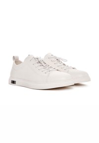 Sneaker in pelle bianca con texture liscia, punta rotonda e suole in gomma piatta, caratterizzati da un accent del nero sul tallone e lacci piatti.