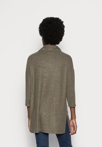 Olivegrüner, oversized Pullover mit umgeschlagenem Kragen und Dreiviertelärmeln. Weicher, strukturierter Stoff mit seitlichen Schlitzen für zusätzlichen Komfort.