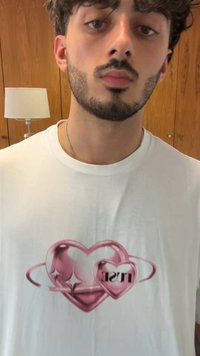 Hvid bomulds t-shirt med et pink hjertegrafik med cirkulært design og teksten "just" i fremtrædende stil.
