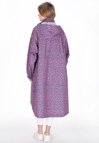 Lång, löst sittande regnrock i lila med rosa leopardmönster, försedd med huva och elastiska ärmslut. Tillverkad av vattenavvisande material.
